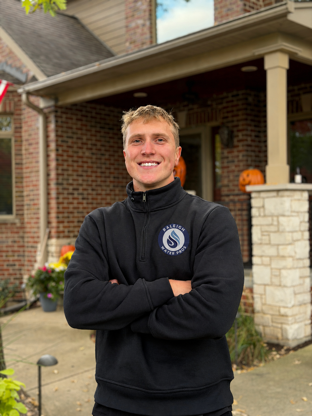 Parker Smith, co-owner of Raleigh Water Pros, wearing a branded quarter-zip in front of a Triangle-area home