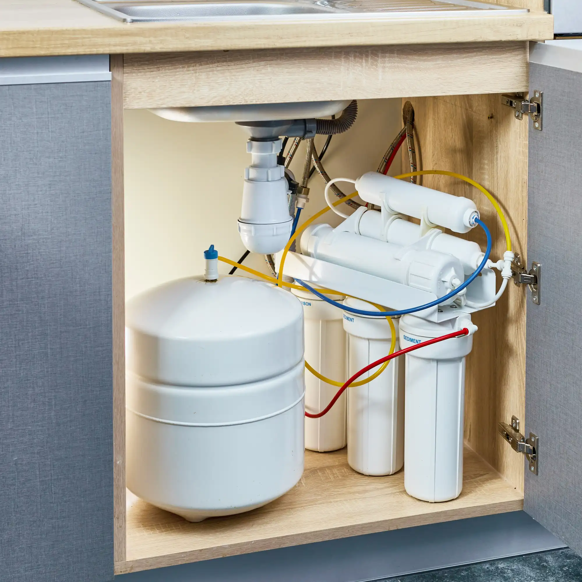 Skilled technician connecting reverse osmosis filters and dedicated faucet with precision tools